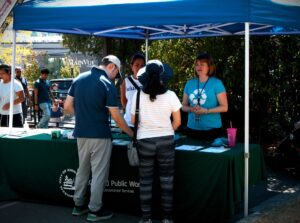 A woman in a blue shirt talks to 2 people at a booth